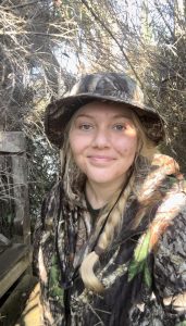 Young woman in camouflage clothing and hat outdoors in nature