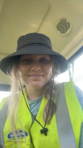 Woman wearing black bucket hat and yellow safety vest indoors