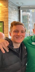 Young man smiling indoors with friend in casual setting