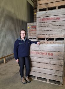 Woman standing beside wooden crates filled with potatoes in warehouse