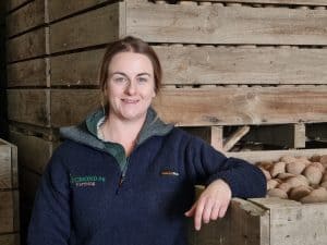 Woman standing next to wooden crates filled with potatoes on farm