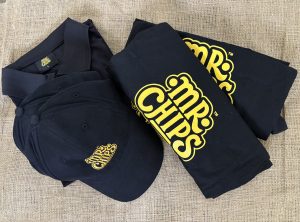 Black Mr. Chips branded t-shirts, polo, and caps on burlap.