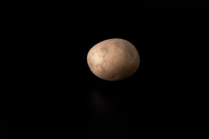 Raw potato on a black background. Healthy and vegetarian food