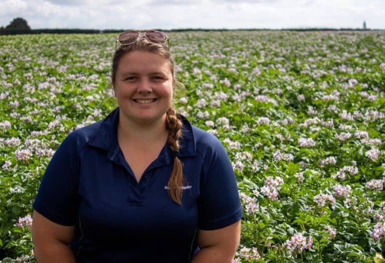 Smiling woman in blue shirt standing in blooming flower field
