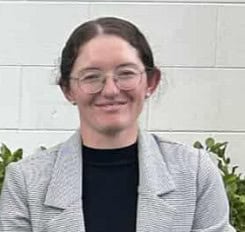 Woman wearing glasses and gray blazer smiling outdoors