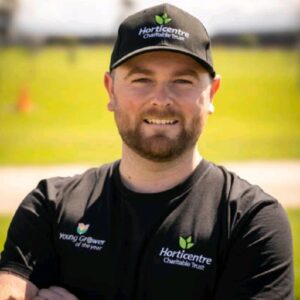 Man wearing Horticentre Charitable Trust cap and shirt outdoors smiling