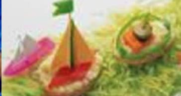 Colorful edible sailboats made with vegetables on grass.