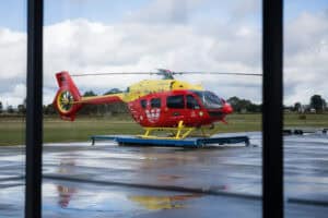 Red and yellow rescue helicopter on wet tarmac outdoors