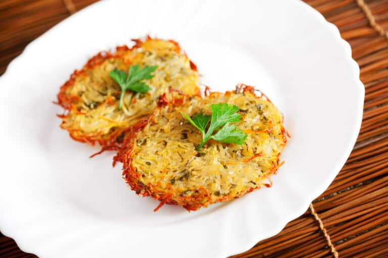 Two crispy herb potato latkes garnished with parsley on white plate