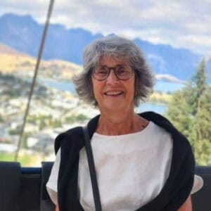 Smiling elderly woman with glasses outdoors with mountain view