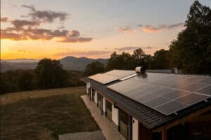 Solar panels on house roof during sunset in countryside.