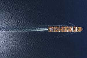 Aerial top view container ship in export and import business and logistics. Shipping cargo to harbor by crane.