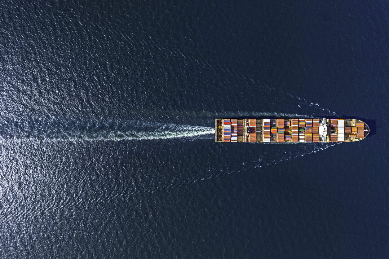Aerial top view container ship in export and import business and logistics. Shipping cargo to harbor by crane.