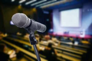 Close-up of microphone with blurred audience and presentation background
