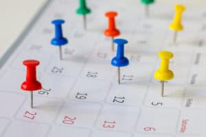 Group of colored thumbtack pins on monthly calendar page