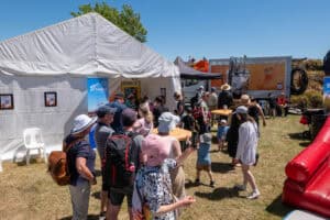 People queuing outside a white tent at outdoor family event