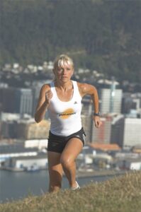 Woman running uphill outdoors wearing "powered by potatoes" tank top.