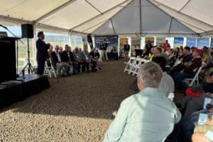 Audience listening to a speaker at an outdoor conference tent event.
