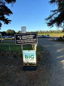 Farm entrance signs with tractor cleaning notice and event welcome.