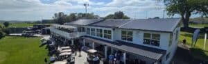 Golf clubhouse with carts and people on sunny day