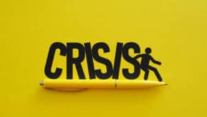 Yellow pen blocking falling crisis text with silhouette figure illustration